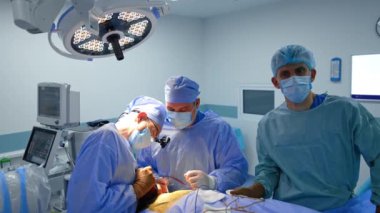 Nörolojik ameliyat yapan bir grup doktor. Erkek ameliyat hemşiresi aletleri baş cerraha verir..