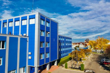 Güneşli bir günde şehir merkezinde modern mavi ve gri bina. Mavi ve gri aksanlı çağdaş bir bina parlak bir gökyüzünün altında görülür.