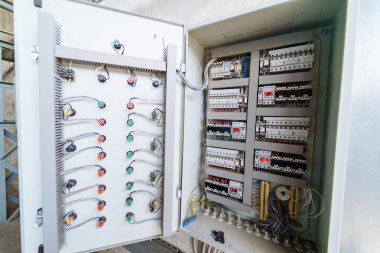 Endüstriyel bölgede elektrik tesisatı ve şalterleri olan kontrol paneli. Kontrol panelinde bir fabrikada makine çalışması için gerekli olan birden fazla kablo ve anahtar bulunmaktadır..