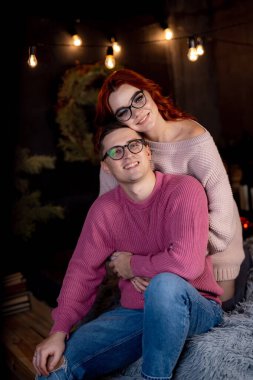 Kışın sıcak ışıkta kazak giyen samimi bir çift. Bir çift, sıcak süveter giyerek, kapalı bir yerde dostça vakit geçirmeyi sever.