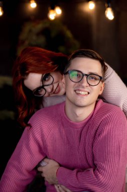 Açık havada rahat bir akşamın tadını çıkaran bir çift. Genç bir çift eşleşen süveterleriyle dışarıda sıcacık sıkı sarılıyor.