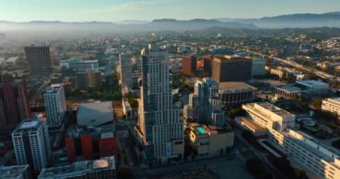 Güneşin batışının ışığı Los Angeles, Kaliforniya, ABD 'nin kentsel manzarasını kaplıyor. Kalın sis, arka plandaki dağları kaplıyor. Üst görünüm.