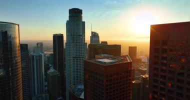 Güneşin batışının altın saatinde Los Angeles 'ın gökdelenlerinin ve panoramasının tepelerini kaplıyor. Amerikan metropolünün finans merkezi binaları arasında insansız hava aracı uçuşu.