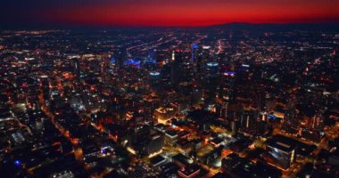 Los Angeles, California, ABD 'nin muhteşem aydınlatılmış gece manzarası. Şehir merkezinin yukarısındaki drone görüntüleri. Metropolün üstündeki kızıl gökyüzü.