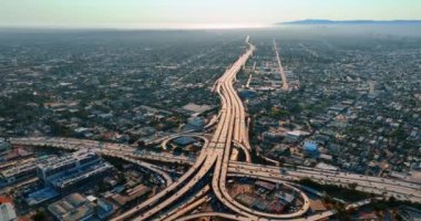 Yoğun trafikte çok katlı bir kavşak. Birden fazla nakliye aracının geçtiği hareketli otoyollar. Gündüz vakti Los Angeles manzarası. Üst görünüm.