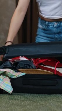 Kadın valizi kapatıyor. Yolculuğun sonunda bavulunu toplayan genç bir kadın. Otel odasında seyahat çantasını kapatmaya çalışan bir kız. Dikey video