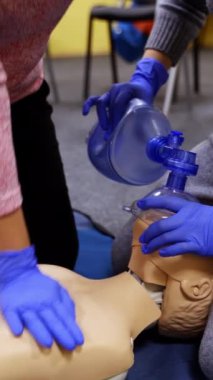Hayat kurtarmak için tıbbi uygulama. Tıp eldivenli öğrenciler eğitim merkezinde bir mankene kalp masajı yapmayı öğreniyorlar. Yetişkinlere suni teneffüs eğitimi ve ilk yardım. Dikey video