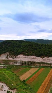 Modern şehirlerden uzak doğa manzaraları. Dağlar, tarım arazileri ve drone görüntülerinden kumlu sahil kenarı olan nehir. Dikey video.