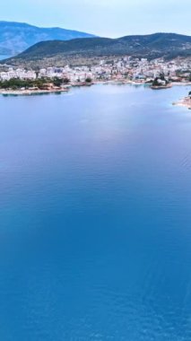 Arnavutluk 'ta deniz kıyısında yaşıyormuş. Deniz kıyısındaki tatil yeri. Su manzarasının üstünden bak. Rıhtıma yakın küçük adalar. Üst Manzara. Dikey video.