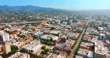 Güneşli bir günde Los Angeles, Kaliforniya 'nın güzel şehir manzarası. Metropolis 'in yollarından birden fazla araba geçiyor. Şehrin yemyeşil arkaplanlı yerleşik tepeleri. Üst görünüm.