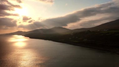 Batan güneş ışınları bulutların arasından karanlık dağlara gider. İrlanda 'da Atlantik Okyanusu' nun en yüksek manzarası.