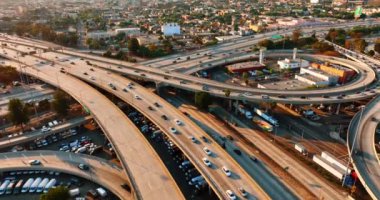 Kavşakta otobanda birden fazla araba çalışıyor ve altında duruyor. Günbatımında Los Angeles, California, ABD 'de hareketli trafik. Üst görünüm.