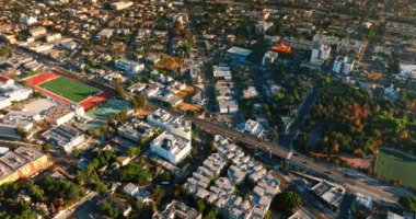 Modern Los Angeles 'ın bir bölgesinin üzerinde uçuyor. Amerikan şehir manzarası ve tepeden bir stadyum..