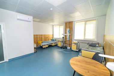 İki yataklı minimalist hastane odası. Geniş bir hastane odasında iki yatak ve tıbbi gereç bulunur.