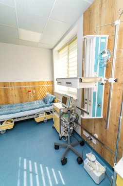Yatak ve tıbbi ekipmanlarla dolu temiz bir hastane odası. Pencereden süzülen yatak, tıbbi ekipman ve güneş ışığının olduğu düzenli bir hastane odası.
