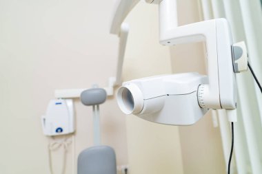 Sandalye ve ekipmanlarla birlikte dişçi muayenehanesi. Temiz bir diş muayenesi odasında hasta bakımı ve kontroller için hazır bir diş sandalyesi ve duvara monte edilmiş ekipman bulunur..