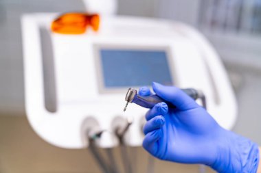 Klinik bir ortamda dişçi ekipmanları sergileniyor. Eldivenli bir el modern bir klinikte dişçi malzemesi bulundurur.