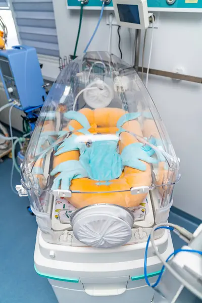 stock image Infant in neonatal intensive care. A newborn is receiving specialized care inside a clear incubator in a busy neonatal intensive care unit designed for vulnerable infants.