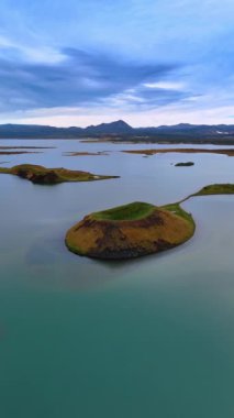 Sudan sarkan çeşitli şekillerde küçük adalar. İzlanda 'nın olağanüstü doğası. Arkaplanda sıradağlar var. Dikey video.