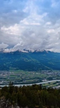 Lichtenstein 'in çarpıcı dağlara dağılmış resimli manzarası. Şehir manzarasının üstündeki gökyüzünü kaplayan kalın bulutlu bir manzara. Dikey video.
