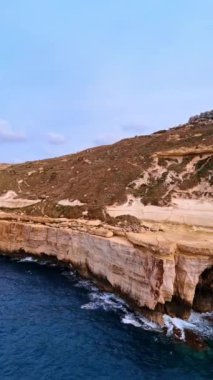 Akdeniz 'in dalgaları kayalıklara çarpıyor. Malta kıyılarında dik dağlar var. Dikey video.