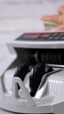 Hesap kağıdı para birimi için otomatik ekipman. Para sayma makinesi dolar sayıyor. Kadın işçi, otomatik makineden 100 USD 'lik bir paket çıkarıyor. Yan görüş. Dikey video