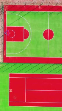 Spor kompleksi. Spor yapmak için yeşil ve kırmızı yapay çimenler. Şehirdeki modern stadyumlar. Üst hava manzarası. Dikey video