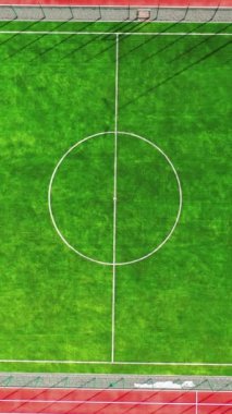 Futbol stadyumu. Yapay çimlerin yeşil arka planında modern bir futbol sahasının beyaz çizgileri var. Üstü açık. Dikey video