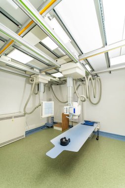 Modern radyoloji odasında gelişmiş görüntüleme. Gelişmiş görüntüleme makinelerinin ve hasta masasının bulunduğu geniş bir radyoloji odası.