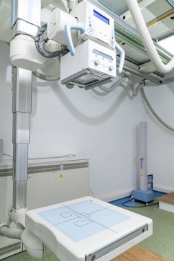 Klinik ortamda modern X-ray cihazı. Yüksek teknolojili bir X-ray cihazı muayene masasının üzerine yerleştirilmiş.