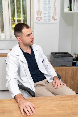 Doctor consulting with a patient. A healthcare professional listens attentively to a patient in a bright consultation room filled with medical charts and equipment. clipart