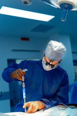 Hassas bir klinik operasyonunda cerrah. Yetenekli bir cerrah, modern bir klinikte güvenlik donanımı giyerken ve elimizdeki işe odaklanırken titizlikle çalışır..