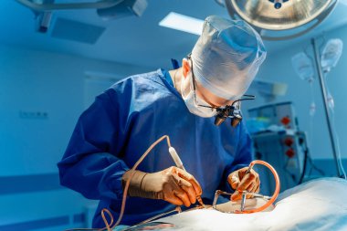 Ameliyathanede çalışan bir cerrah. Yetenekli bir cerrah, modern bir ameliyathanede parlak ve steril bir ışık altında cerrahi bir prosedür uygular..