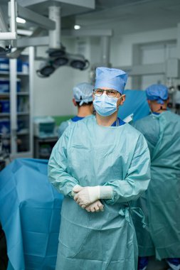 Cerrahi ekip steril odada hazırlanıyor. Ameliyat maske ve önlüklü bir cerrahi ekip tıbbi ekipmanlarla bir ameliyathanede ameliyata hazırlanıyor..