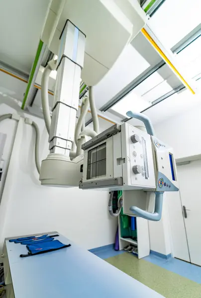 stock image Modern X-ray machine in a bright medical facility. A cutting-edge X-ray machine hangs from the ceiling in a well-lit medical room, ready for diagnostic imaging procedures.