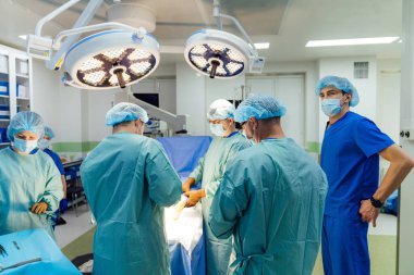 Cerrahi ekip modern ameliyathanede. Kendini adamış bir cerrahi ekip, gündüz saatlerinde iyi donanımlı bir ameliyathanede hassas bir prosedür uygular..