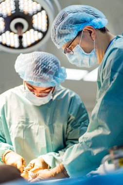 Tıbbi ekip tarafından ameliyat devam ediyor. Bir tıbbi ekip ameliyathanede işbirliği yapıyor. Parlak ışıklar ve katı protokoller altında cerrahi bir prosedüre odaklanıyor..