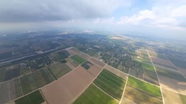 Geniş tarlalar ve kırsal yerleşim alanları. FPV bulutlar arasında karanın drone görüntüleri.