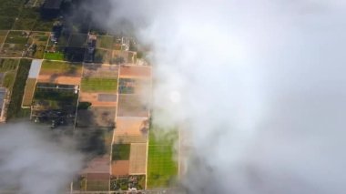 Beyaz bulutların içinde. Bulutların arasında uçarak yerleşim olan manzaranın görüntüsünü ortaya çıkarıyorlar. FPV insansız hava aracı görüntüleri.
