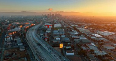 Metropolis 'e çok şeritli otobandan birçok araç girip çıkıyor. Gün batımında Los Angeles, Kaliforniya 'nın puslu manzarasına hava perspektifi.