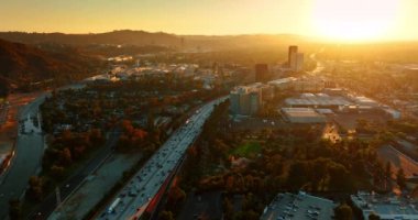 Yüzlerce aracın geçtiği çok şeritli bir otobana yaklaşıyoruz. Batan güneş Metropolis 'in manzarasını aydınlatıyor. Hava görünümü.