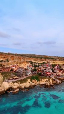 Deniz suyunun üzerindeki kayalıklara evler inşa edildi. İrlanda kıyı şeridindeki kayalık araziye hava perspektifi. Dikey video.