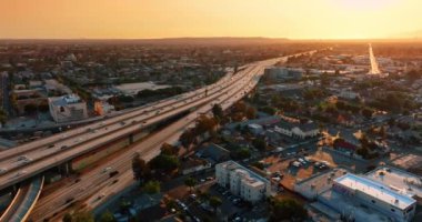 Şehir merkezine girip çıkan birden fazla arabası olan otobanlar. Günbatımında modern Los Angeles, Kaliforniya, ABD 'de çılgın trafik. Hava görünümü.