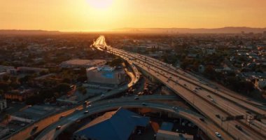 Gün batımında turuncu ışıkla aydınlanan yoğun bir kavşak. Los Angeles, Kaliforniya 'nın engin şehir manzarası.