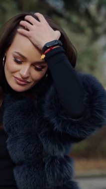 Açık havada sosyetik bir kızın portresi. Parkta bir fincan kahveyle kameraya poz veren güzel görünümlü esmer manken. Ağır çekim. Dikey video