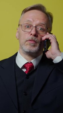 Telefonu olan kıdemli bir iş adamı. Stüdyoda zarif kostümlü bir adam cep telefonuyla konuşuyor ve kameraya bakıyor. Dikey video