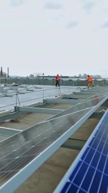 Düz bir çatıda güneş paneli kurulumu. Modern güneş enerjisi santralinin inşası. Güneş çiftliğinde çalışan teknisyenler. Güneşten gelen alternatif enerji. Dikey video