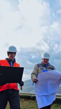 Güneş çiftliğinde çalışan işçiler. Mühendisler güneş panelleri kurulumundan bahsediyor. Dizüstü bilgisayarı ve projesi olan teknisyenler yeni ekolojik istasyonun inşasını tartıştılar. Dikey video