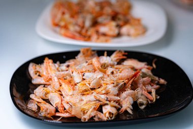 Kenarlı karides tabağı. Çeşitli karidesler güzel bir şekilde siyah bir tabakta sunuluyor, iştah açıcı bir deniz ürünleri tabağı sunuluyor..