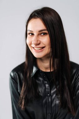 Siyahlı kadın arka planda gülümsüyor. Uzun saçlı genç bir kadın şık bir siyah gömlek giyerken sıcak bir şekilde gülümsüyor..